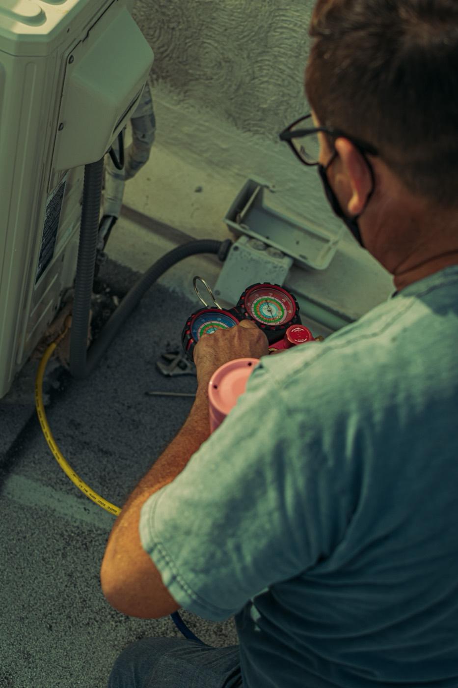 Technician checking AC refrigerant pressure with manifold gauges to diagnose warm-air problems