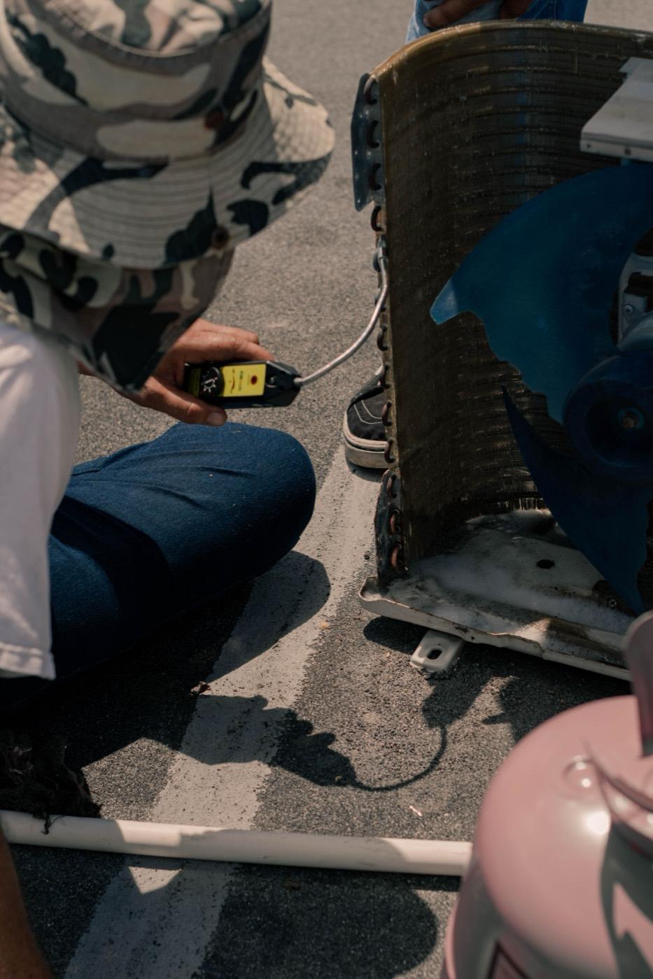 Technician using a leak detector on an AC evaporator coil to find the source of a water leak