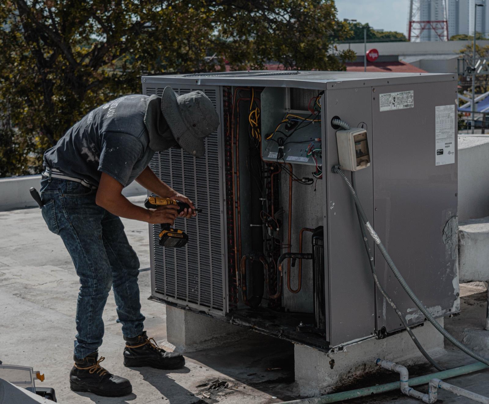Broward AC Guys technician making an emergency repair on an open AC condenser unit
